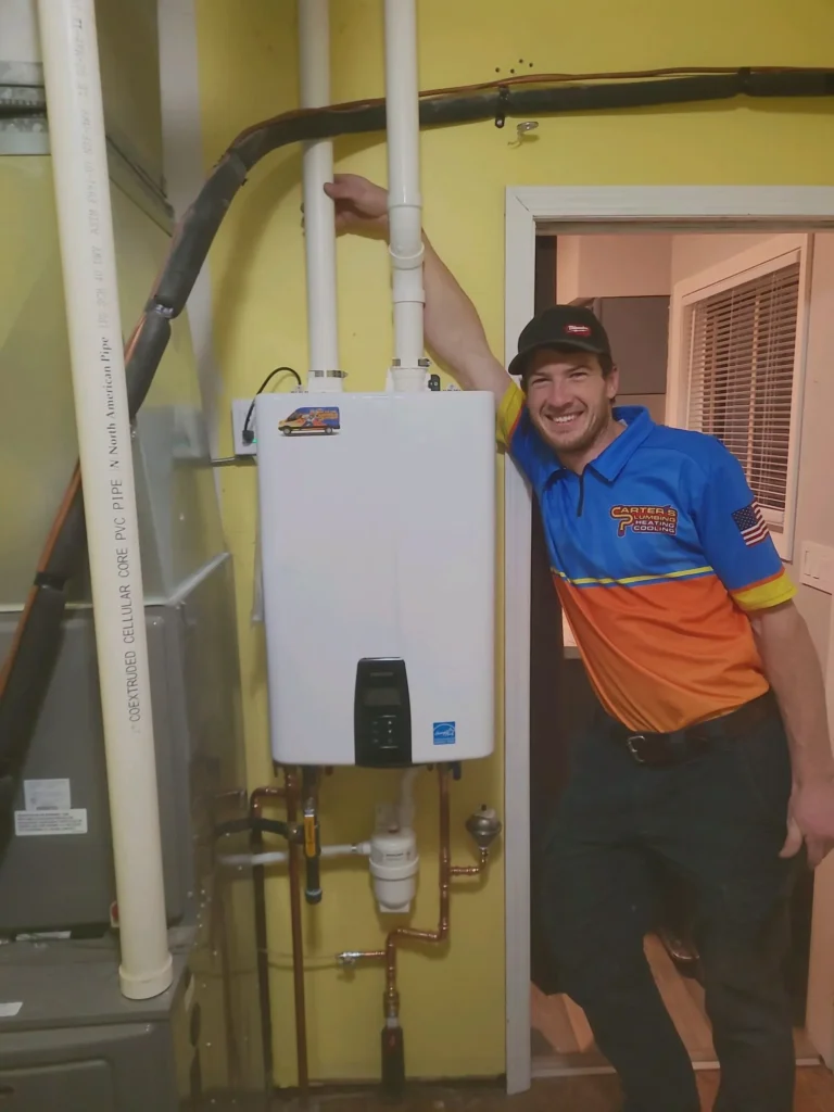 A person in a uniform poses with a tankless water heater in a utility room.